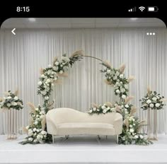 a white couch sitting on top of a table covered in flowers and greenery next to a wall