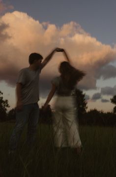 a man and woman standing in the grass with their arms around each other as they dance