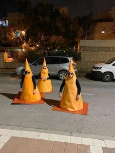 three people dressed in orange cones on the street