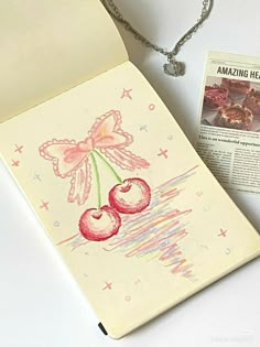 a piece of paper with an image of cherries on it next to a necklace