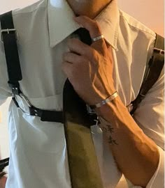 a man is adjusting his tie while wearing a white shirt and black suspenders,