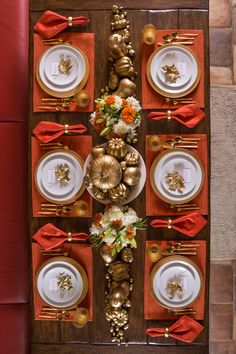 the table is set with gold and white plates, orange napkins, and flowers