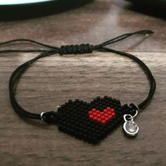 a black and red beaded heart bracelet on a table