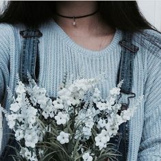 a woman wearing overalls holding a bouquet of flowers