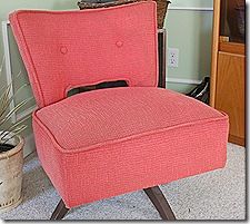 a red chair sitting on top of a carpeted floor next to a potted plant