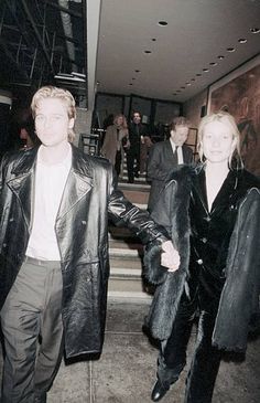 a man and woman are walking down the stairs in black leather jackets with fur collars