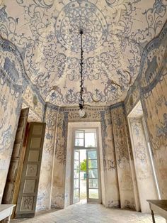 an ornately painted ceiling in the middle of a room with large doors and windows