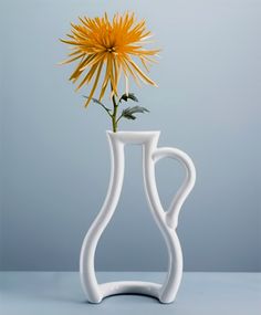 a white vase with a yellow flower in it