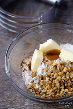 a bowl filled with nuts and butter on top of a wooden table next to a knife