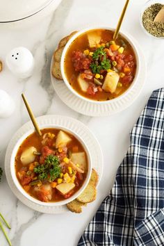 two bowls of vegetable soup with bread on the side