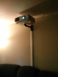 a projector mounted to the side of a wall with a light shining on it