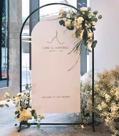 a wedding sign with flowers on it in front of a window and chinese characters below