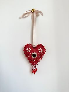 a red heart ornament hanging on a white wall