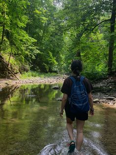 a person walking across a river in the woods