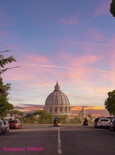 an image of the dome of a church at sunset or dawn with cars parked in front