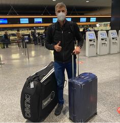 a man wearing a face mask with luggage at an airport