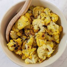 a white bowl filled with cauliflower and a wooden spoon