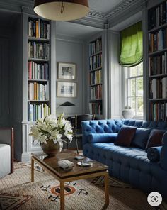 a living room with blue couches and bookshelves full of books in it