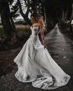 a woman in a white dress is walking down the road