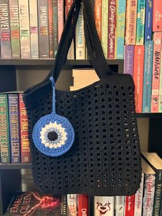 a crocheted bag with an evil eye on it hanging from a book shelf