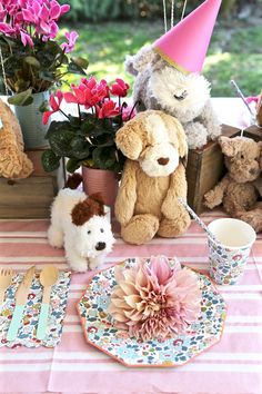 stuffed animals are sitting at a table with plates and cups