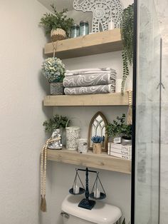 bathroom shelves with towels, plants and other items on them in a white walled room