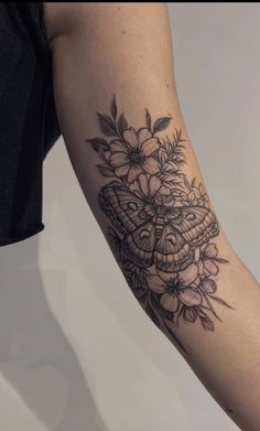 a woman's arm with a butterfly and flowers tattoo on the left side of her arm