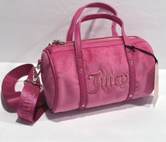 This Juicy Couture crossbody bag is a must-have for any fashion-forward woman. The bag features a beautiful pink velour exterior with a quilted finish and heart-shaped logo accent. It has a zip closure and double handles for versatile carrying options. The bag measures 8.5 inches in width, 4.5 inches in height, and 5 inches in depth, making it a small but practical size for everyday use. The bag also includes inner pockets for easy organization and a detachable strap for customizable carrying. The strap is adjustable and made of faux leather, matching the gold-plated hardware. This bag is perfect for travel, parties, or casual outings. Add a touch of designer love to your outfit with this Juicy Couture Queen of Everything Mini Barrel crossbody bag. Queen Of Everything, Easy Organization, Everything Pink, Pink Velvet, Women Accessories Bags, Juicy Couture, Bags Handbags, Fashion Forward, Crossbody Bag