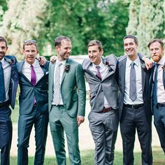 a group of men standing next to each other wearing suits and ties on the grass