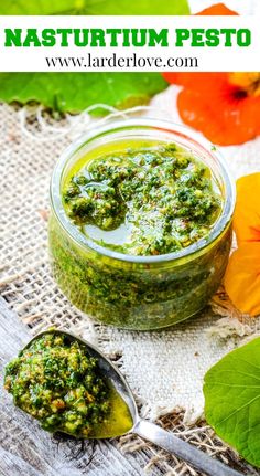 a jar filled with pesto sitting on top of a wooden table next to flowers