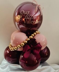 some balloons are stacked on top of each other and tied with a pink ribbon that says our little valentine