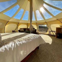 a bed sitting inside of a large tent under a skylight on top of a floor