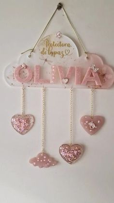 a pink and white sign with hearts hanging from it's sides on a wall