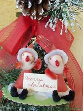 a christmas ornament with two little gnomes holding a sign