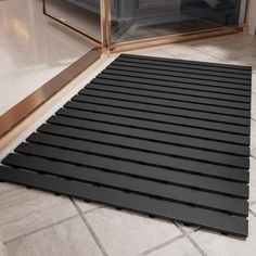 a black mat on the floor in front of a glass door with a microwave behind it