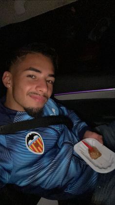 a man sitting in the back seat of a car holding a plate with food on it