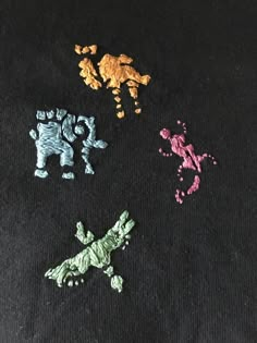 four different colored handmade animals on a black surface with one small animal in the middle