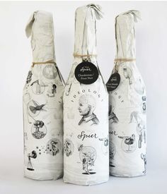 three wine bottles wrapped in white paper with drawings on them and tied to each other