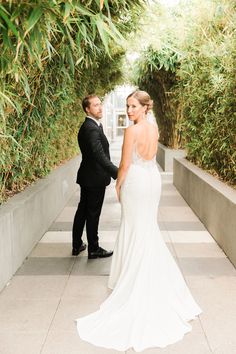 a bride and groom standing in front of some trees