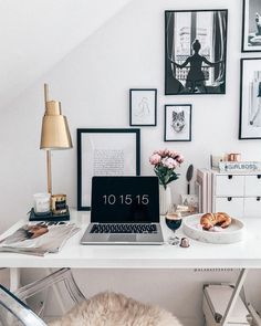 a white desk with pictures on the wall and a laptop sitting on top of it