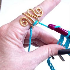 someone is knitting something with yarn and crochet hooks on their fingers, which are attached to each other