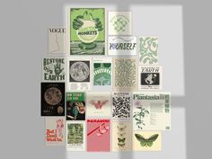 an assortment of posters are displayed on the wall in front of a gray background with green and white designs