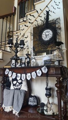 a table with halloween decorations on it in front of a stair case, clock and staircase railing