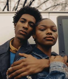 two people standing next to each other in front of a van