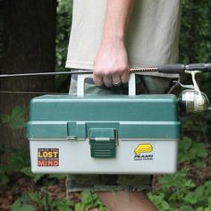 a man is holding a fishing box in his hands and pulling the rod from it