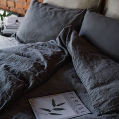 a book is laying on the bed with some pillows and blankets in front of it