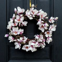 a wreath with pink and white flowers hanging on a black door