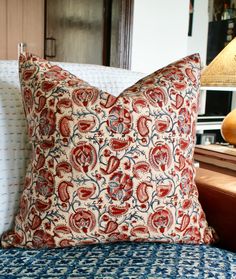 a red and blue pillow sitting on top of a bed