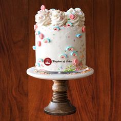 a cake with white frosting and sprinkles sitting on top of a wooden table