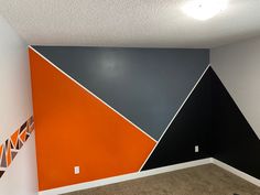 an empty room with orange, black and grey walls in it's corner area